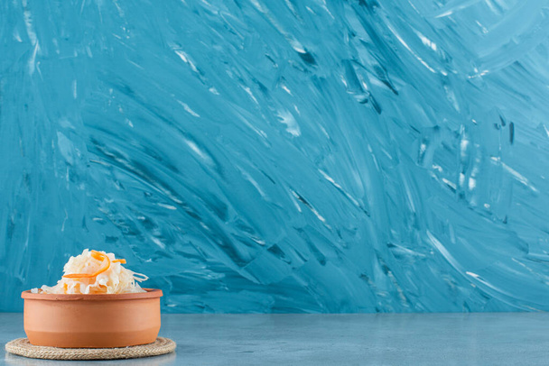 青の背景に、トリビア上のボウルにニンジンと発酵ザウアークラウト。高品質の写真 - 写真・画像