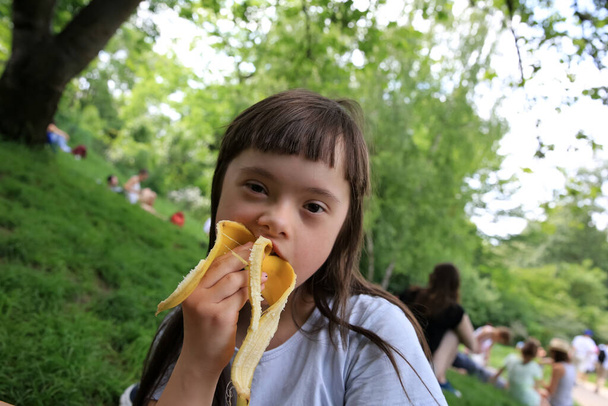 jong meisje eten banaan in het park - Foto, afbeelding