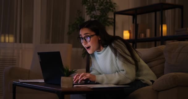 Женщина празднует успех онлайн поздно ночью на ноутбуке - Кадры, видео
