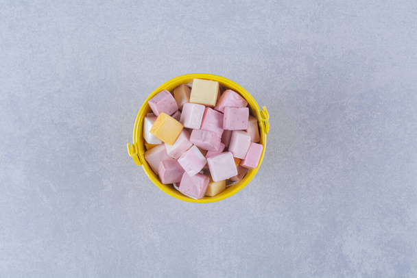 Žlutý kbelík růžové a žluté sladké cukrovinky Pastila. Kvalitní fotografie - Fotografie, Obrázek
