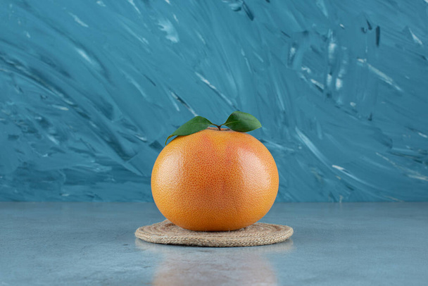 Ripe juicy orange on a trivet, on the marble background. High quality photo - Photo, Image