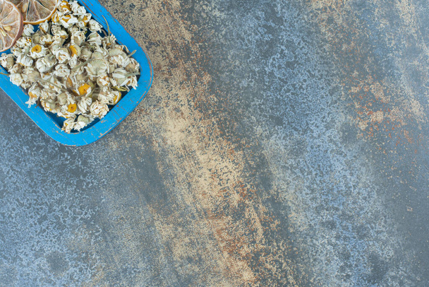 Szárított kamilla és citrom kék tányéron. Kiváló minőségű fénykép - Fotó, kép