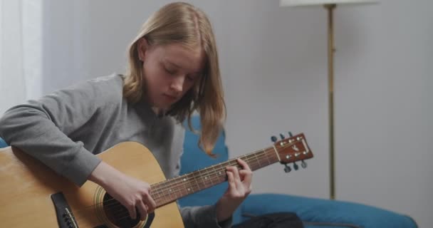 Een jong meisje speelt enthousiast de klassieke gitaar. Ze schudt haar hoofd op het ritme van de melodie. Close-up opname. - Video