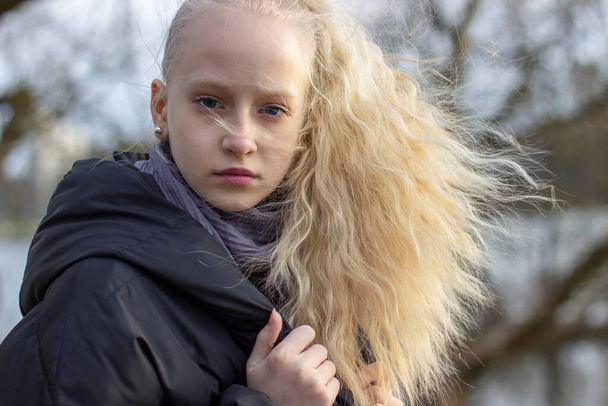 portrait of a teenage girl with blond hair in an early spring park - Фото, изображение