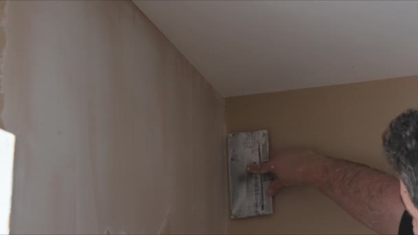 Travailleur plâtré le mur de placoplâtre est cloison sèche pendant la rénovation de la maison - Séquence, vidéo