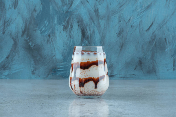Bolas de chocolate en un vaso de leche, sobre el fondo azul. Foto de alta calidad - Foto, Imagen