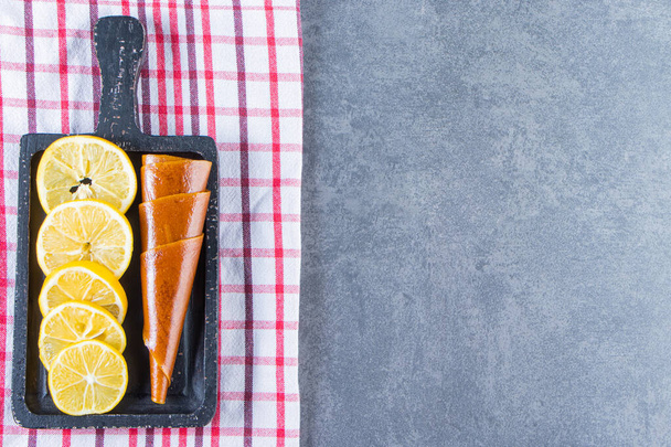Agria y cortar el limón en una tabla en la toalla de té, sobre el fondo de mármol. Foto de alta calidad - Foto, imagen
