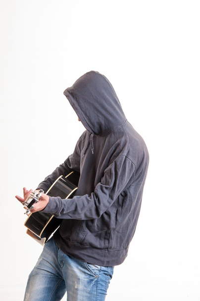 Sad teenager in hoodie playing acoustic guitar - Foto, imagen