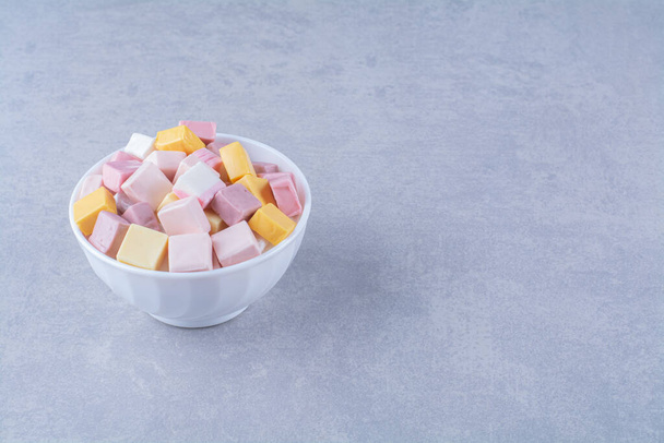 Белая миска с розовыми и желтыми сладкими кондитерскими изделиями Pastila. Высокое качество фото - Фото, изображение