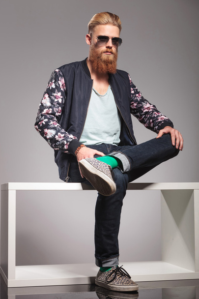 бородатый молодой человек сидит на маленьком столе
 - Фото, изображение