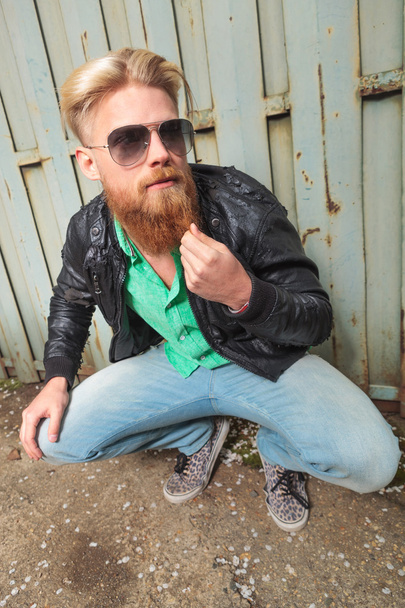 squatted young man plays with beard - Photo, Image