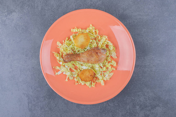 Kip trommelstok en gebakken aardappelen op oranje bord. Hoge kwaliteit foto - Foto, afbeelding