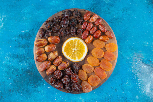 Cortar el limón y las frutas secas en una tabla, sobre el fondo azul. Foto de alta calidad - Foto, imagen