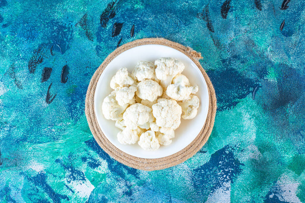 A bowl of cauliflower on a trivet , on the blue background. High quality photo - Photo, Image