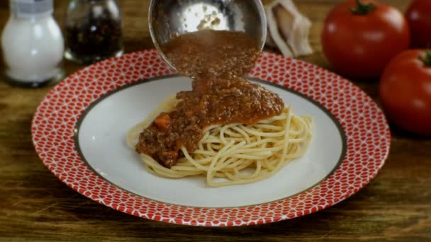 Bolognese sauce putting in cooked spaghetti or tagliatelle pasta in white plate, in restaurant or home kitchen. Sprinkles parmesan. Homemade recipe cooking. - Footage, Video
