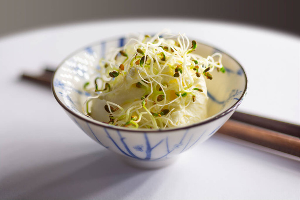 Fresh sprouts, germinated seeds with cream cheese in a small bowl on a white table with chopsticks - Photo, Image