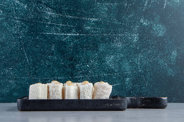Tabla de cortar negro de deliciosas golosinas con nueces sobre fondo de piedra. Foto de alta calidad - Foto, Imagen