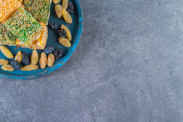 Турецкие деликатесы и изюм на деревянной тарелке, на мраморном фоне. Высокое качество фото - Фото, изображение