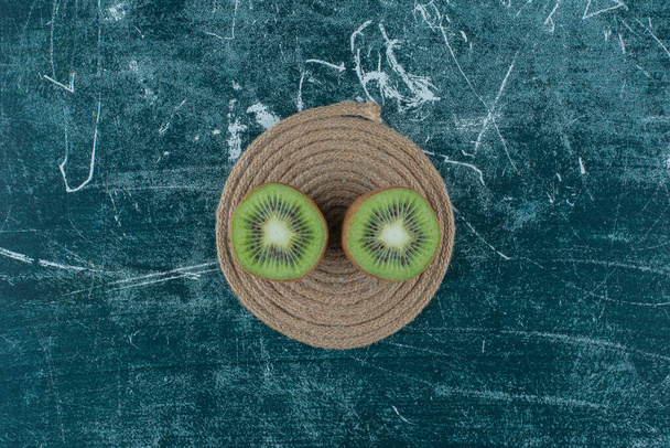 Dos piezas de kiwi en trivet, sobre el fondo de mármol. Foto de alta calidad - Foto, Imagen