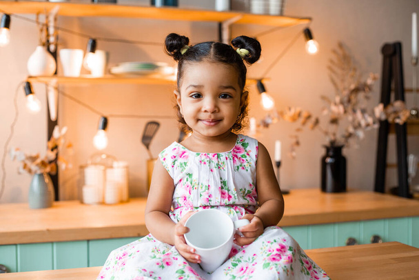 schattig klein Afrikaans Amerikaans meisje thuis in keuken - Foto, afbeelding