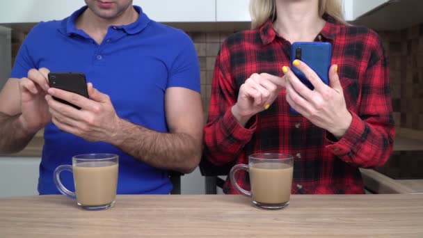 Genç bir çift, aile, mutfakta akıllı telefonları olan kadın ve erkek. İnternet bağımlılığı kavramı - Video, Çekim