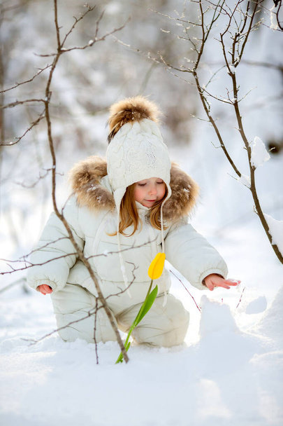 little girl with yellow tulip in snowy scene - Photo, Image
