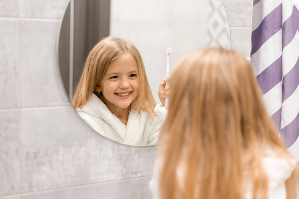 Симпатична дівчина в туалеті миє зуби у ванній
  - Фото, зображення