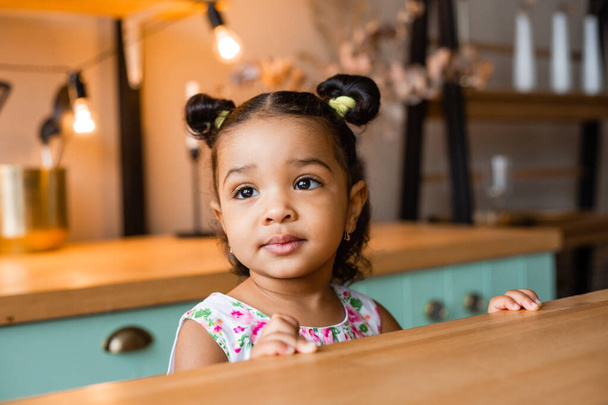 schattig klein Afrikaans Amerikaans meisje thuis in keuken - Foto, afbeelding