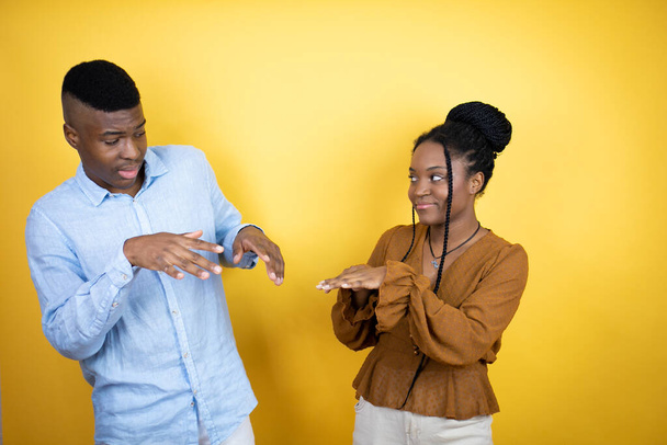 Молоде африканське американське подружжя стоїть над жовтим фоном огидного виразу, незадоволене і страшне, чинячи огиду, тому що реагує відразливо. Поняття тривоги - Фото, зображення