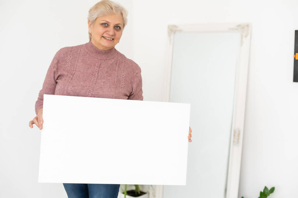 пожилая женщина держит фото холст - Фото, изображение