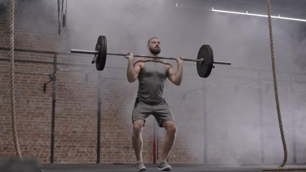 Amplio tiro de deportista caucásico muscular usando ropa deportiva haciendo ejercicio con barra en el gimnasio - Metraje, vídeo