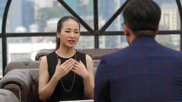 Verrouillage d'une femme d'affaires asiatique et d'un homme d'affaires assis sur un canapé devant l'autre et ayant une conversation importante - Séquence, vidéo