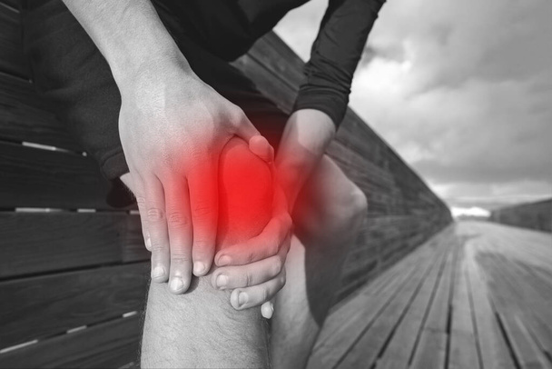 Человек с болью в колене, суставах, артрите или сухожилиях. Бегун держит и массирует колено из-за травмы. Травма от физических упражнений. - Фото, изображение