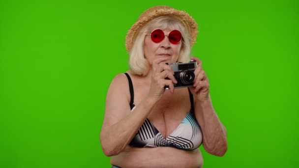 Senior žena turista fotograf fotografování na retro fotoaparátu a úsměv na pozadí chroma klíč - Záběry, video