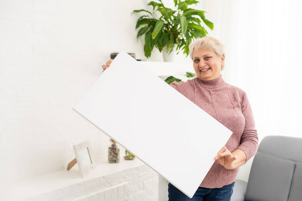 elderly woman holds a photo canvas - Photo, Image