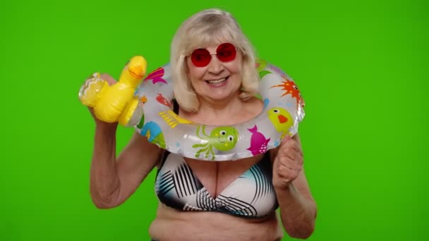 Turista senior en traje de baño bailando, celebrando, jugando con el juguete inflable del pato, anillo de goma - Metraje, vídeo