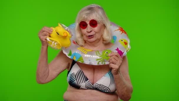 Senior γυναίκα τουρίστρια σε γυαλιά ηλίου χορό, παίζει με φουσκωτά πάπια παιχνίδι, καουτσούκ δαχτυλίδι κολύμπι - Πλάνα, βίντεο