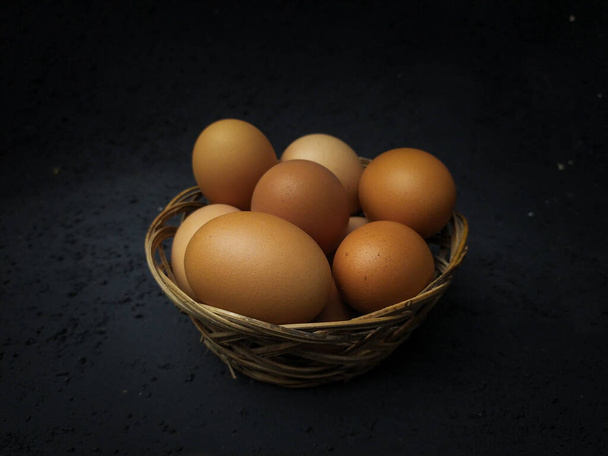 Αυγά κοτόπουλου στο καλάθι με σκούρα backgroud - Φωτογραφία, εικόνα