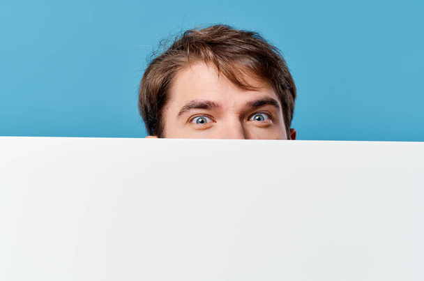 man peeking out from behind banner cropped view advertisement copy space blue background - Фото, изображение
