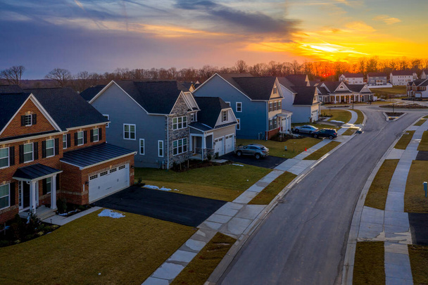 Αεροφωτογραφία μιας σειράς πολλαπλών ιστορία μονοκατοικίες ακίνητα ακίνητα σε μια νέα κατοικημένη προαστιακή γειτονιά δρόμο στο Μέριλαντ ΗΠΑ με δραματικό πολύχρωμο ηλιοβασίλεμα ουρανό - Φωτογραφία, εικόνα