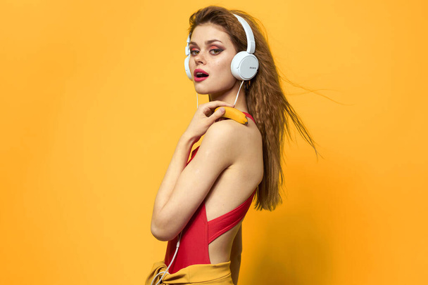 ヘッドフォンの女性は音楽の感情のライフスタイル楽しい黄色の背景を聞く - 写真・画像
