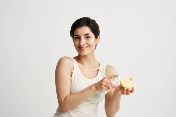 Beautiful brunette in a white T-shirt Sponge in the hands of skin care - Foto, afbeelding