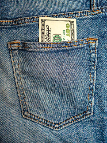 стодолларовая купюра торчит из заднего кармана его синих джинсов. - Фото, изображение