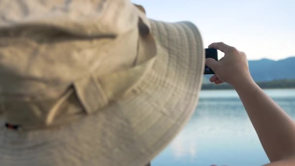 Giovani turisti di sesso femminile che scattano smartphone per scattare foto di belle montagne e laghi al tramonto. Stile di vita e concetti di vacanza. - Filmati, video