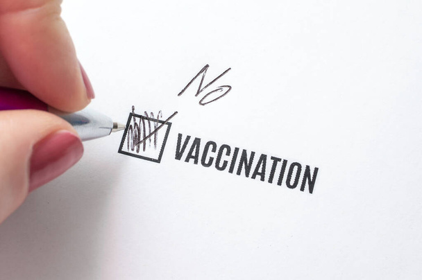 Vaccination - Non. La réponse négative au questionnaire. La main d'une jeune femme remplit un questionnaire - Photo, image