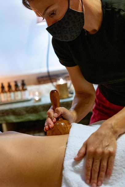 Masseurin gibt einem Klienten eine Massage mit Holzmassage - Foto, Bild