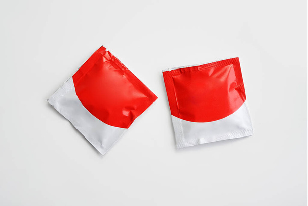 Márkátlan alkoholos törlőkendő vagy fertőtlenítő szalvéta fehér alapon izolált piros és fehér csomagolásban. Kozmetikai csomagolás mockup. Felülnézet másolási térrel. - Fotó, kép