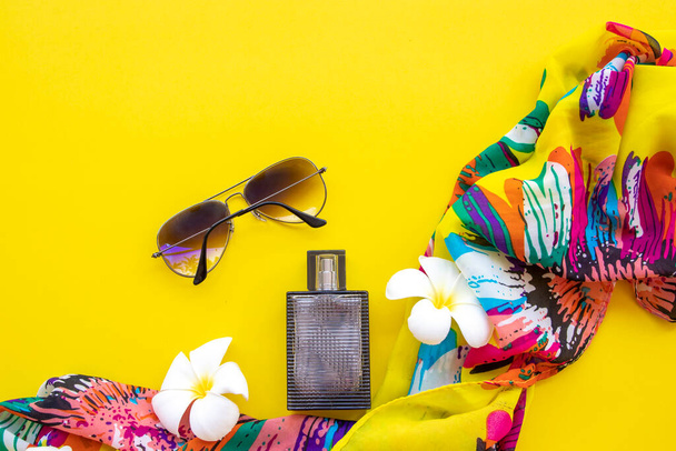 parfém, žlutý šátek a sluneční brýle doplňky životního stylu žena relaxační uspořádání byt ležel styl na pozadí žluté - Fotografie, Obrázek