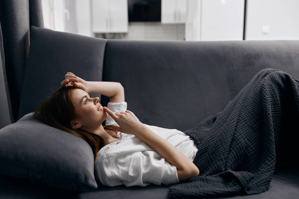 rudowłosa kobieta leżąca na kanapie i gestykulująca rękami z boku - Zdjęcie, obraz