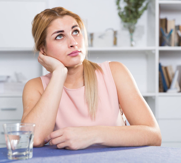 Sad woman is sitting at the table alone and upset - Photo, Image